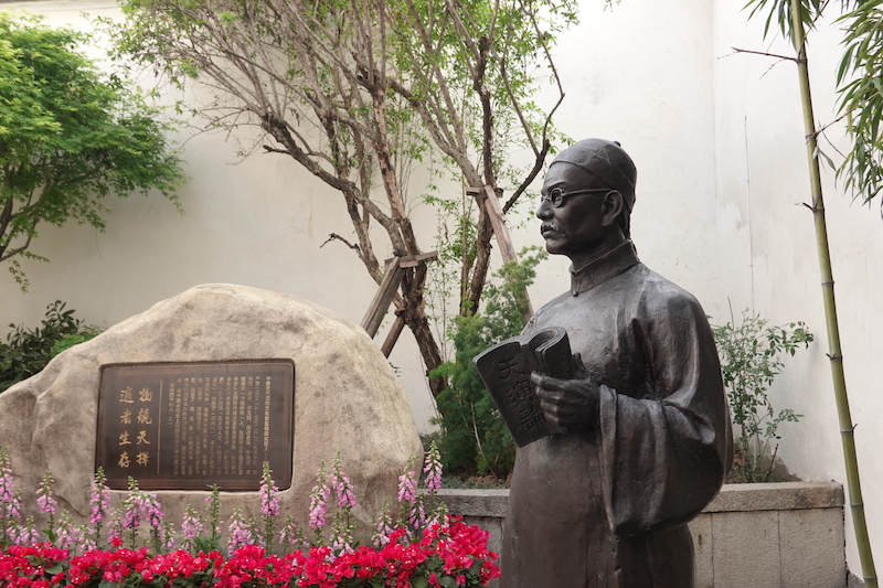 △嚴(yán)復(fù)故居里的銅像。他手捧《天演論》，旁邊石頭上的銅牌寫著“物競(jìng)天擇，適者生存”。（總臺(tái)央廣記者潘毅拍攝）